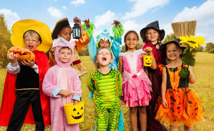 Eight children in various Halloween costumes posing in a field