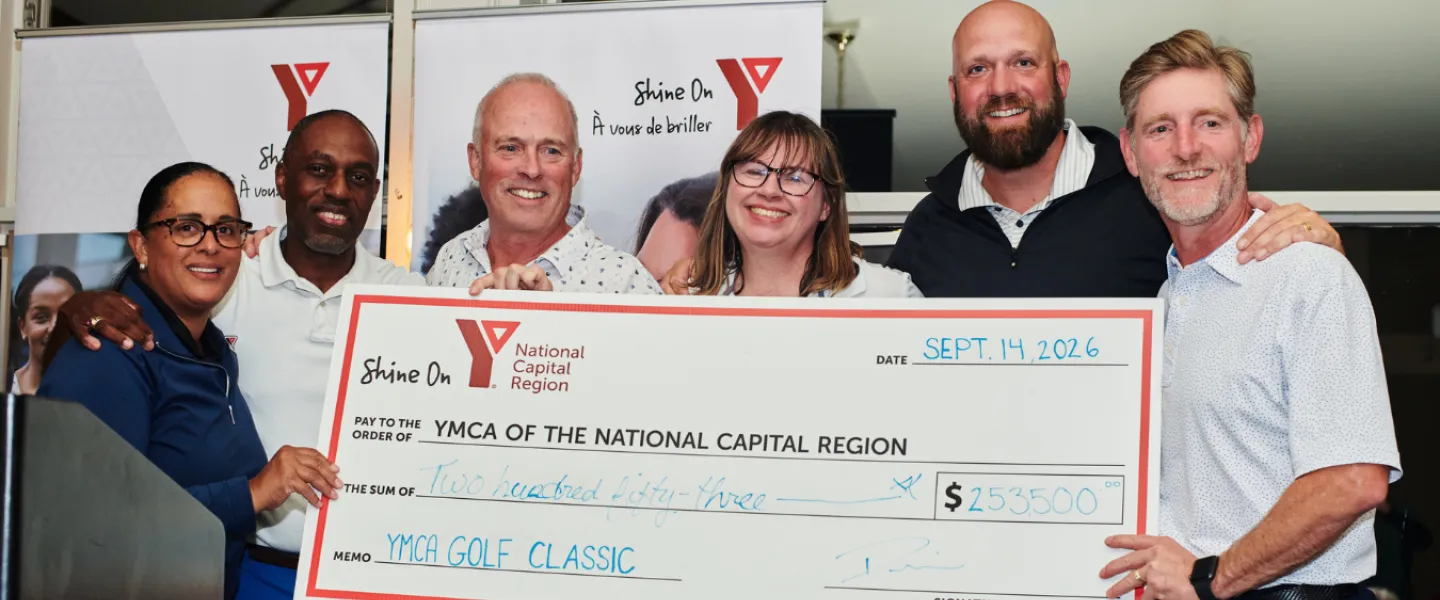 Seven people, including Y team members, partners, and sponsors, holding a large cheque of $253,500 to the YMCA.