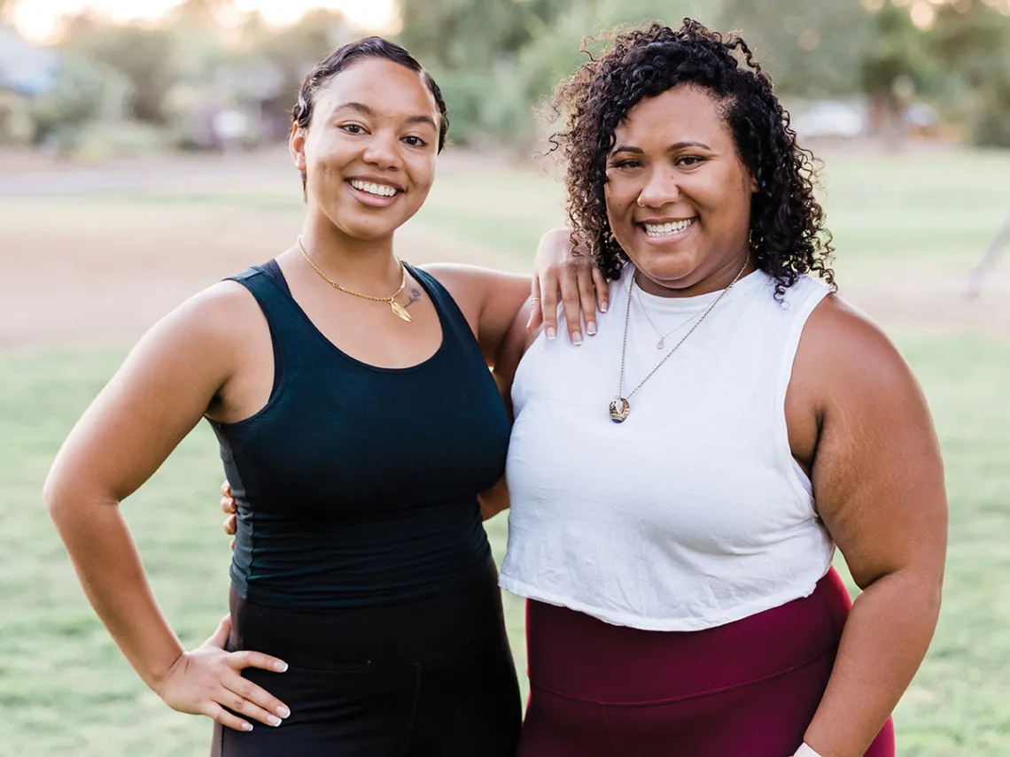 Two women pose together smiling in an outdoor setting.