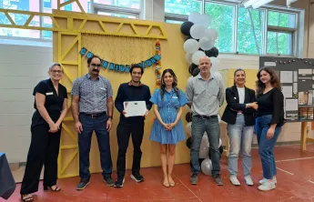 Sushant holding a Power of Trades graduation certificate and standing alongside YMCA staff