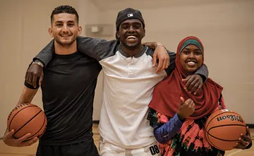 Three young adults playing basketball in the gymnasium.