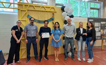Sushant holding a Power of Trades graduation certificate and standing alongside YMCA staff